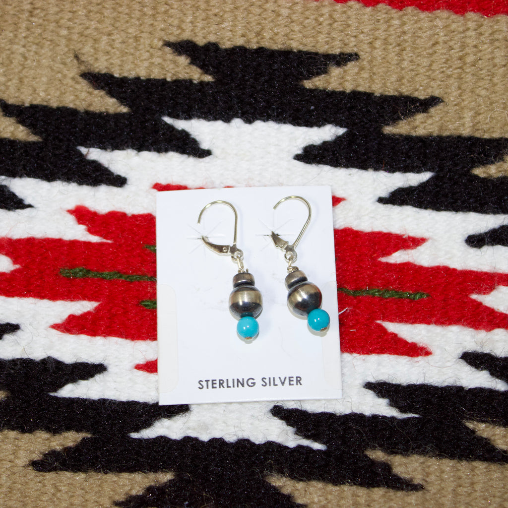 Dangle earrings with two Navajo pears and one small turquoise bead at the bottom.