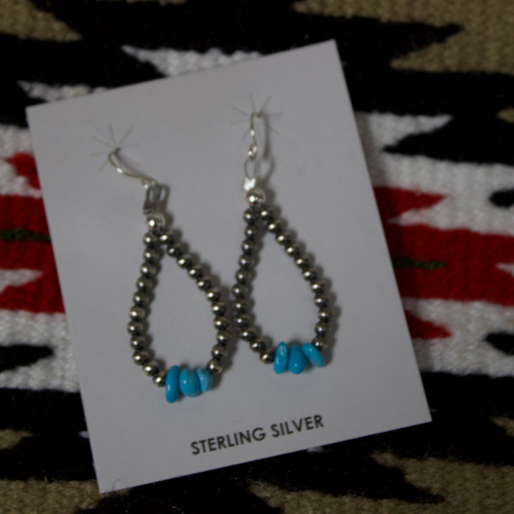 Teardrop shaped earrings with small Navajo pearl earrings with three turquoise stones at the bottom. 