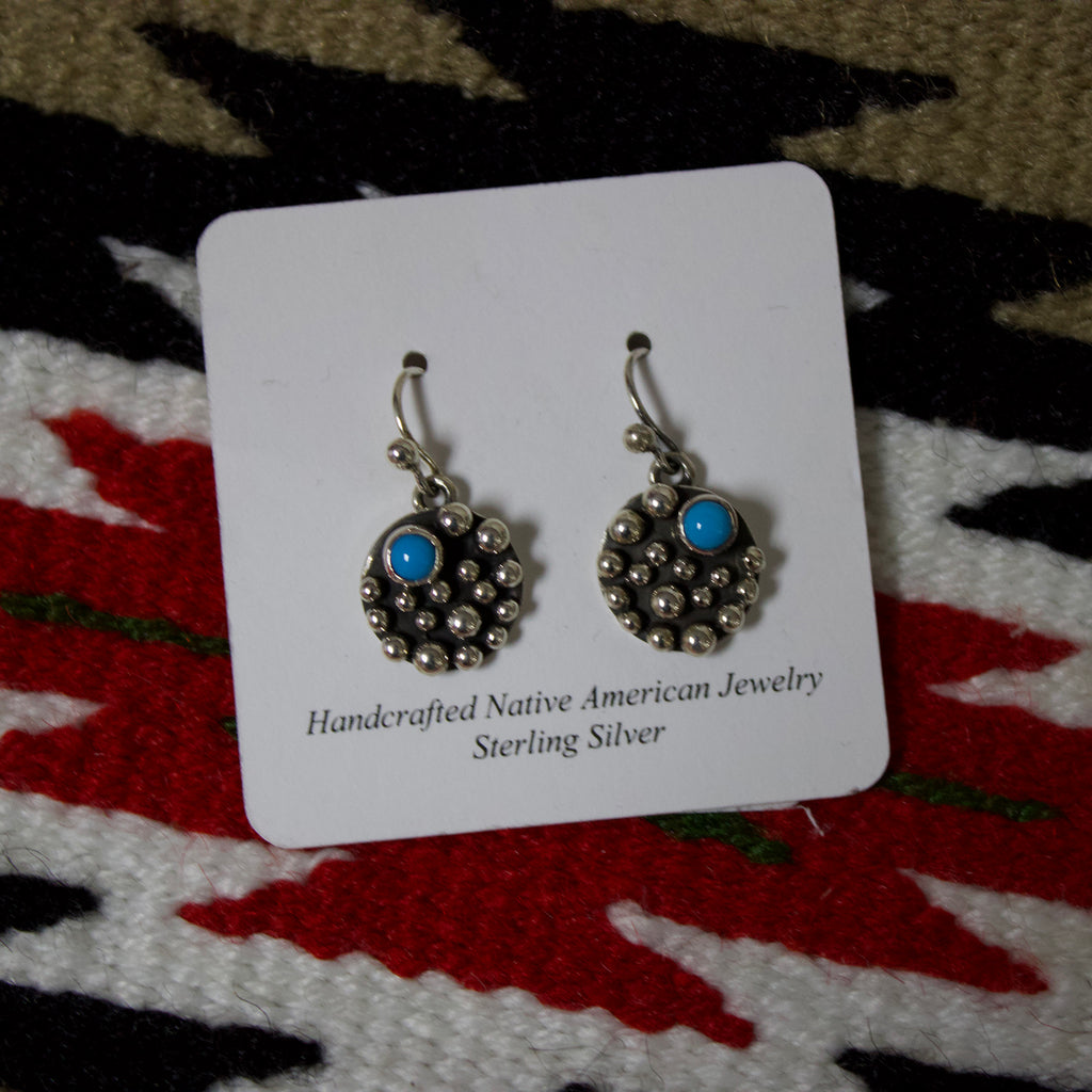 Small circle sterling silver earrings with silver dots and one small turquoise stone.