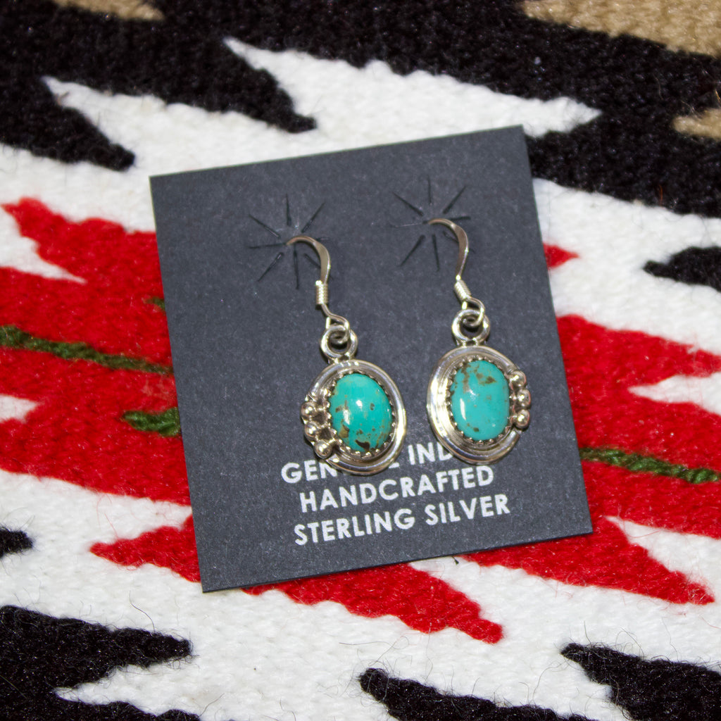 Small sterling silver earrings with oval shaped stones and silver detailing around it. 