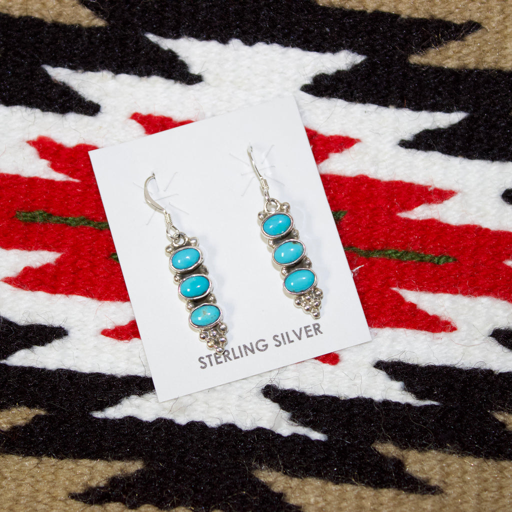 Sterling silver drop earrings with three turquoise oval stones.