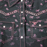 Close up view of the shirt, it has pink pearl snap buttons and pink stitching. 