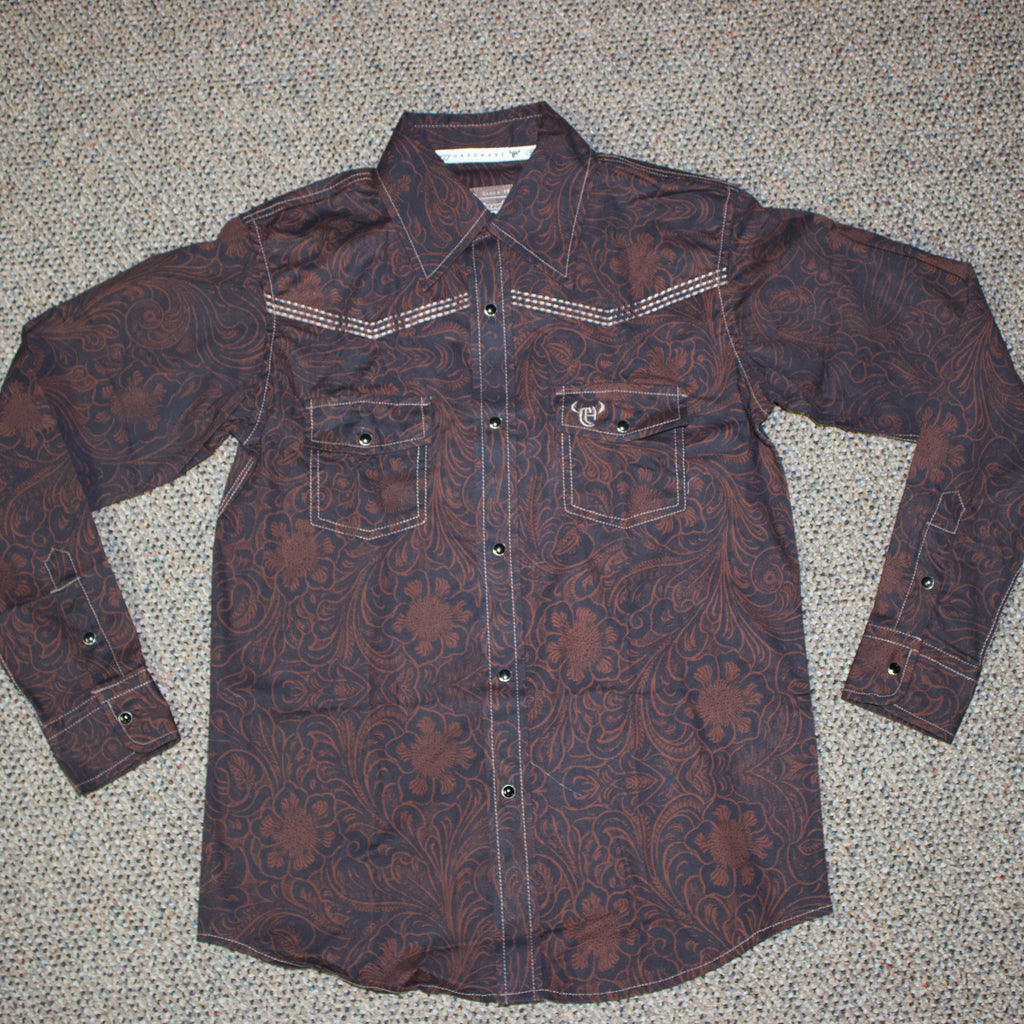 Flat lay of brown tooled floral long sleeve shirt with black pearl snaps. 