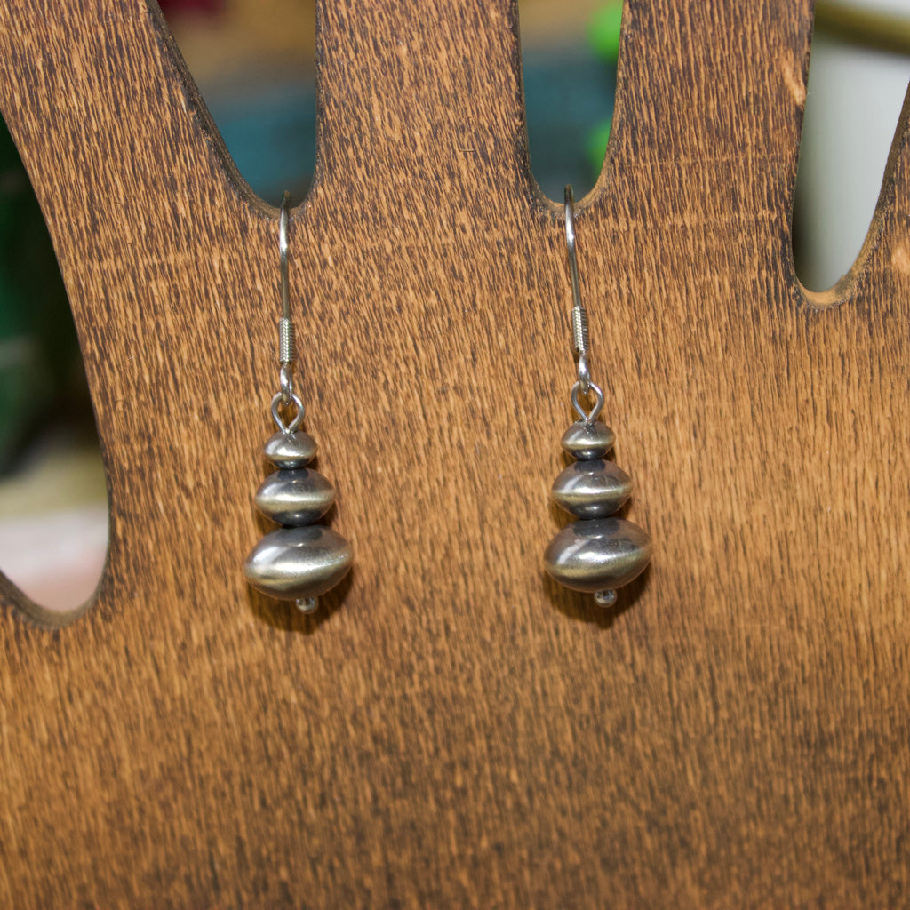 Navajo style pearl earrings with three graduated saucer shaped pearls stacked on each other.
