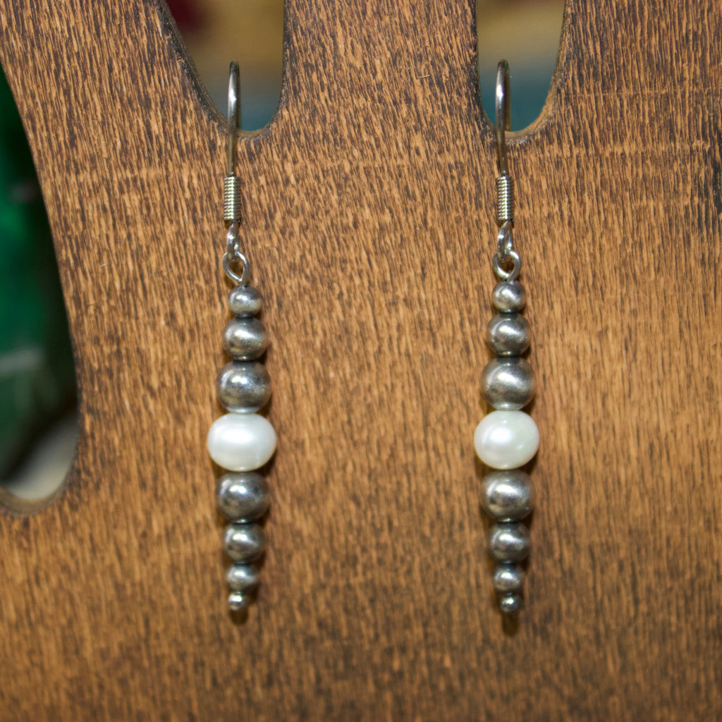 Navajo style pearl earrings that are graduated with the bigger pearls towards the middle and one white pearl in the center.