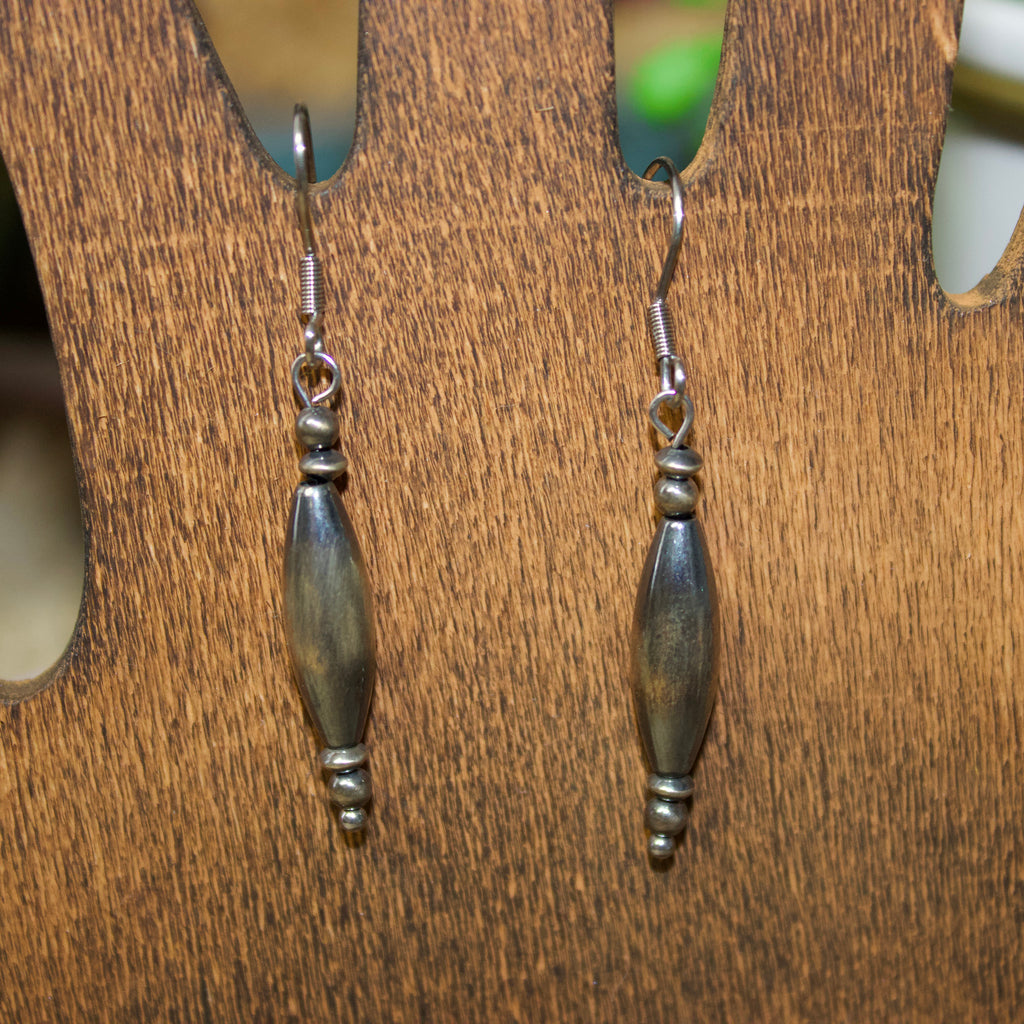 Navajo style pearl earrings with two small pearls on top, torpedo shaped pearl in the middle, and three small pearls on the bottom.
