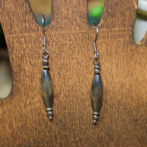 Navajo style pearl earrings with two small pearls on top, torpedo shaped pearl in the middle, and three small pearls on the bottom.