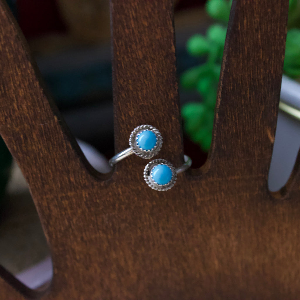 Sterling silver ring with two small turquoise stones that are offset from each other. 