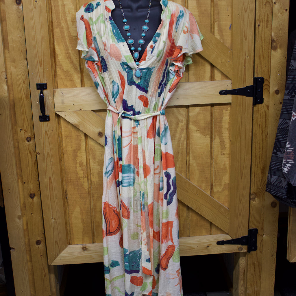 Light orange floor length dress with a tie string around the waist, a button neckline, and folded pleats.