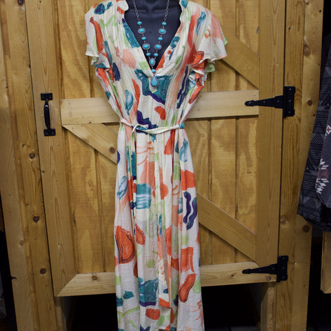 Light orange floor length dress with a tie string around the waist, a button neckline, and folded pleats.