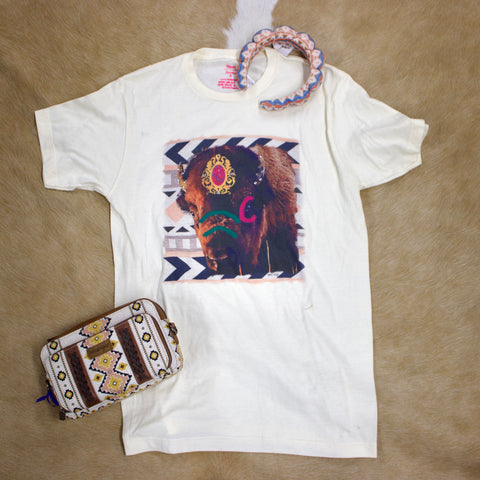 Flat lay of cream colored painted buffalo t shirt with headband and purse laying next to it. 
