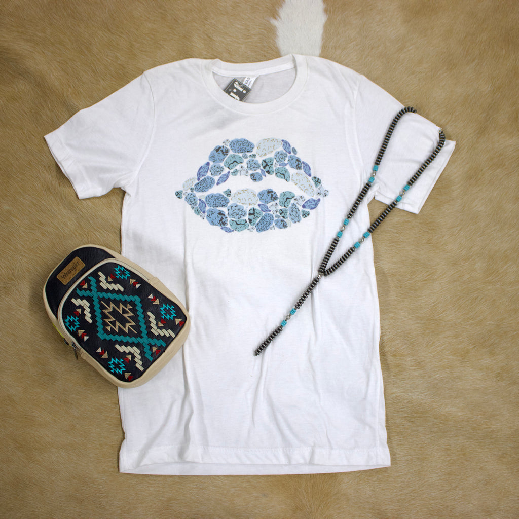 Flat lay view of white t-shirt with turquoise leopard print lips with a necklace and purse sitting next to it. 