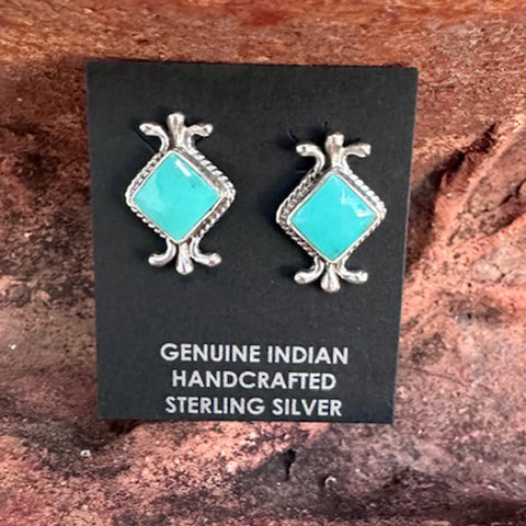 Pair of turquoise and silver earrings on a black card with text about authenticity.