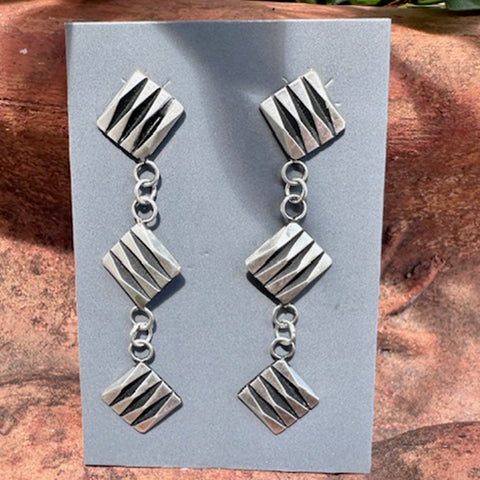 Sterling Silver geometric earrings on a gray card with a wooden background