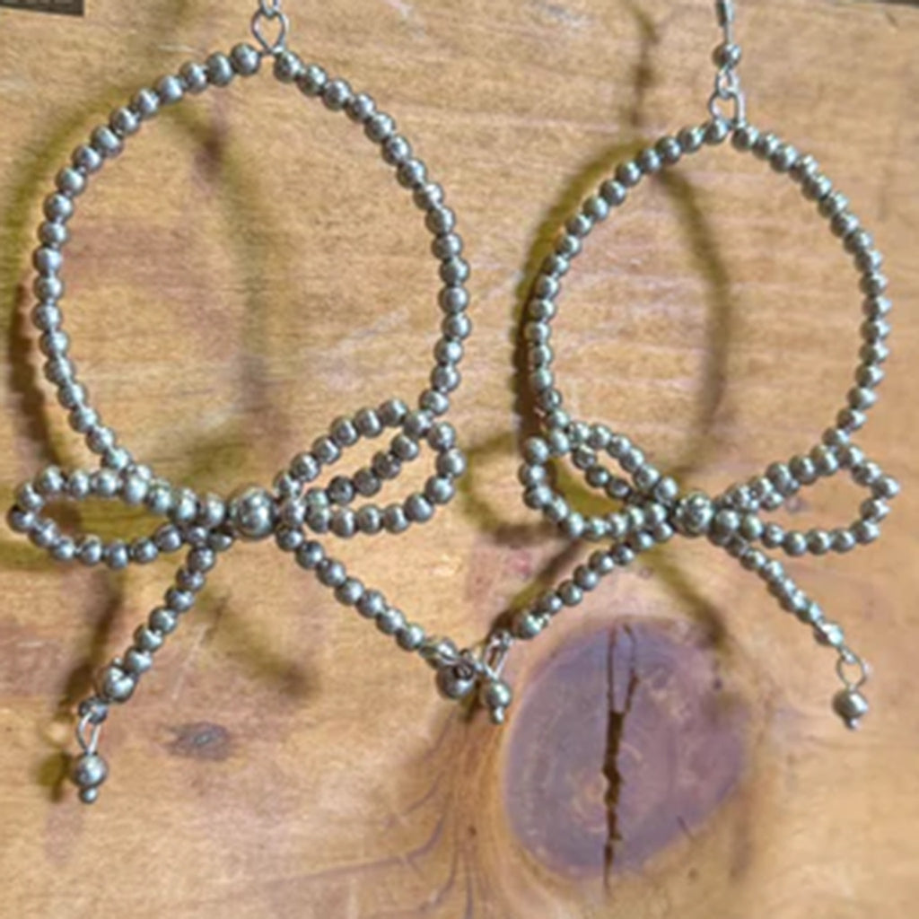 Grey pearl earrings with a large hoop and a bow on the bottom. 