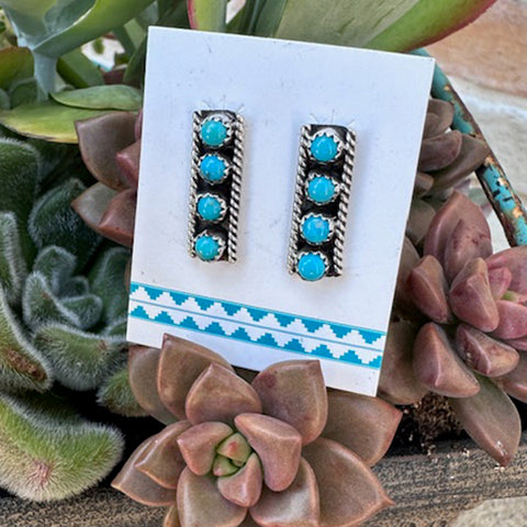Pair of turquoise Zuni Bar Earrings with 4 small round stone on a white card with blue design, surrounded by succulents.
