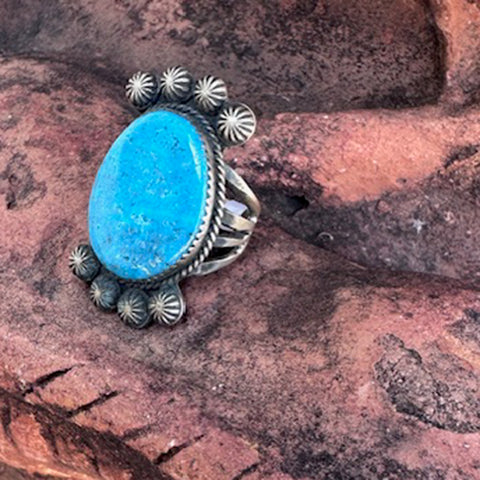 Turquoise stone ring with silver band on a textured brown surface