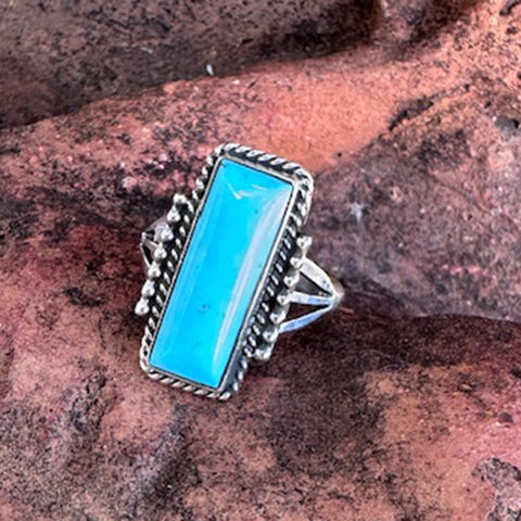 Kingman Turquoise bar ring with silver band on a textured stone background