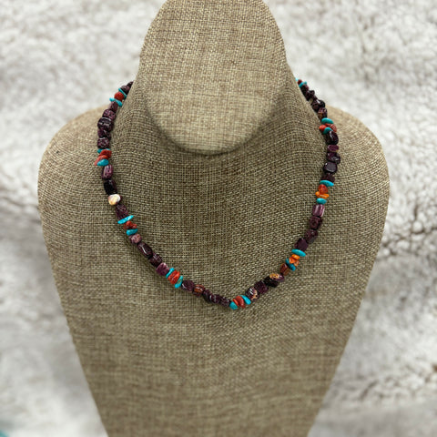 Purple beaded necklace with turquoise, red, and orange beads sitting on a mannequin 