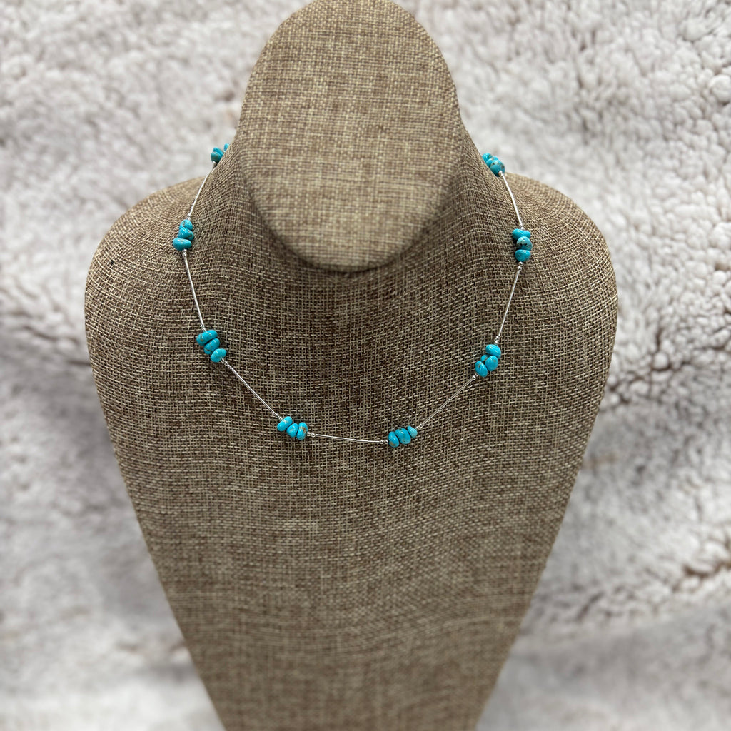 Sterling silver neck lace with silver beads and clusters of Kingman Turquoise stones, sitting on the mannequin 