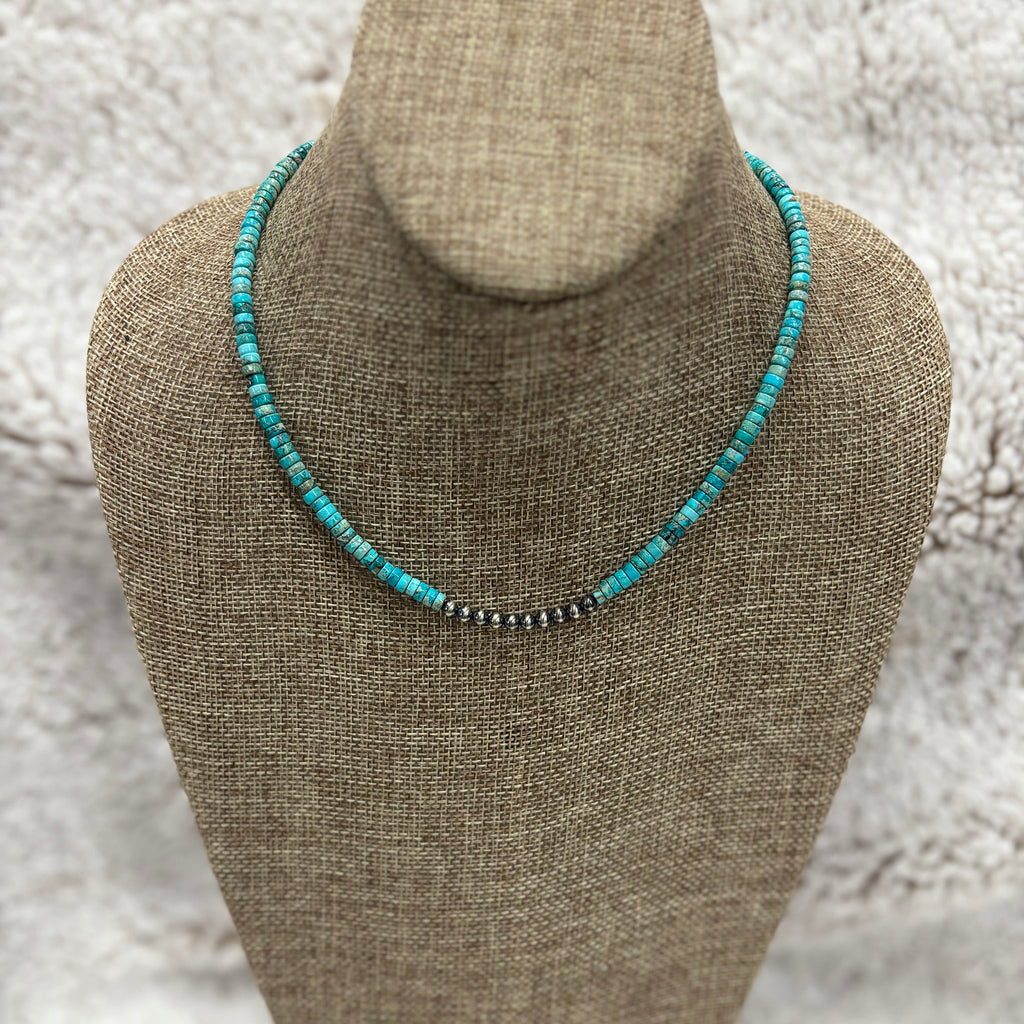 Beaded necklace with tubular turquoise stones and small Navajo pearls in the center, sitting on mannequin 