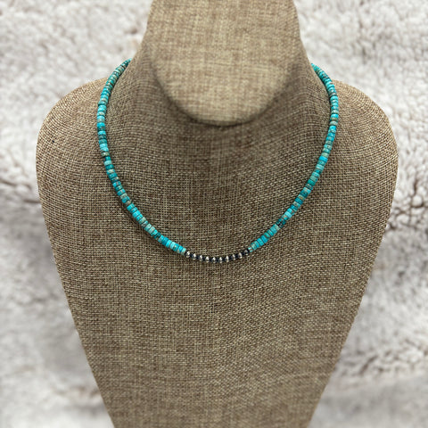 Beaded necklace with tubular turquoise stones and small Navajo pearls in the center, sitting on mannequin 
