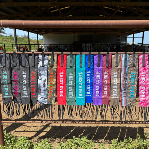 Line of assorted tail bags hanging on fence. 