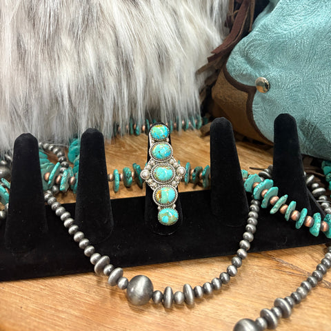 Long sterling silver ring with 5 Kingman turquoise stones in a vertical line and sterling silver accents next to the middle stone 