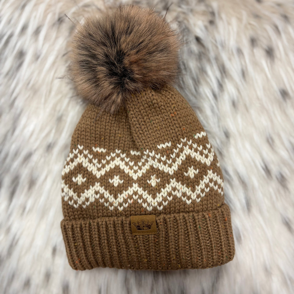 Brown knit hat with white zig zag design and a brown fur ball on top 