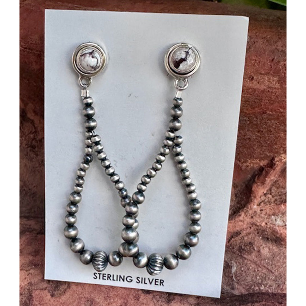 Pair of silver beaded earrings on a white card with 'Sterling Silver' text, against a textured brown background.