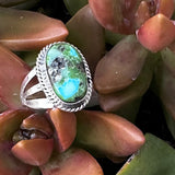 Sonoran Gold Oval ring with a green stone on a background of succulent plants