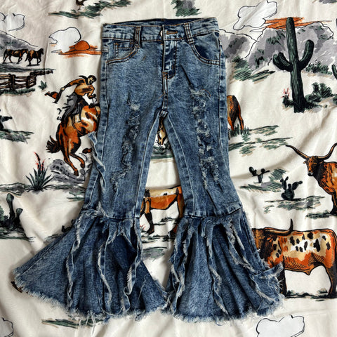 Flat lay picture of the front of the jeans, light and dark blue color with distressed details on the front of the legs and bell bottoms with strings falling down.