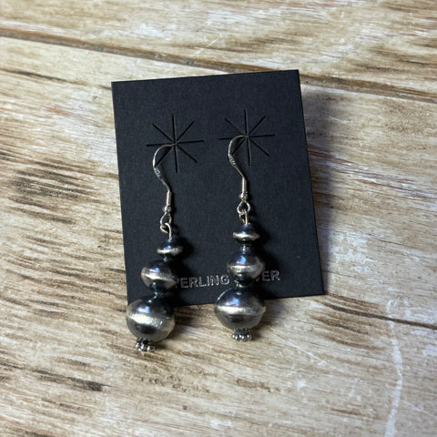 Navajo pearl earrings with the saucer shaped pearls stacked on top of each other, pearls get bigger as they go down and have a hook earring.