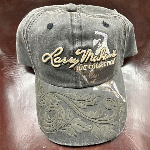 Black faded ball cap with tan stitched "Larry Mahan's Hat Collection" written on the front and printed graphic bull rider behind the letters. Floral deign on the brim of the hat. 