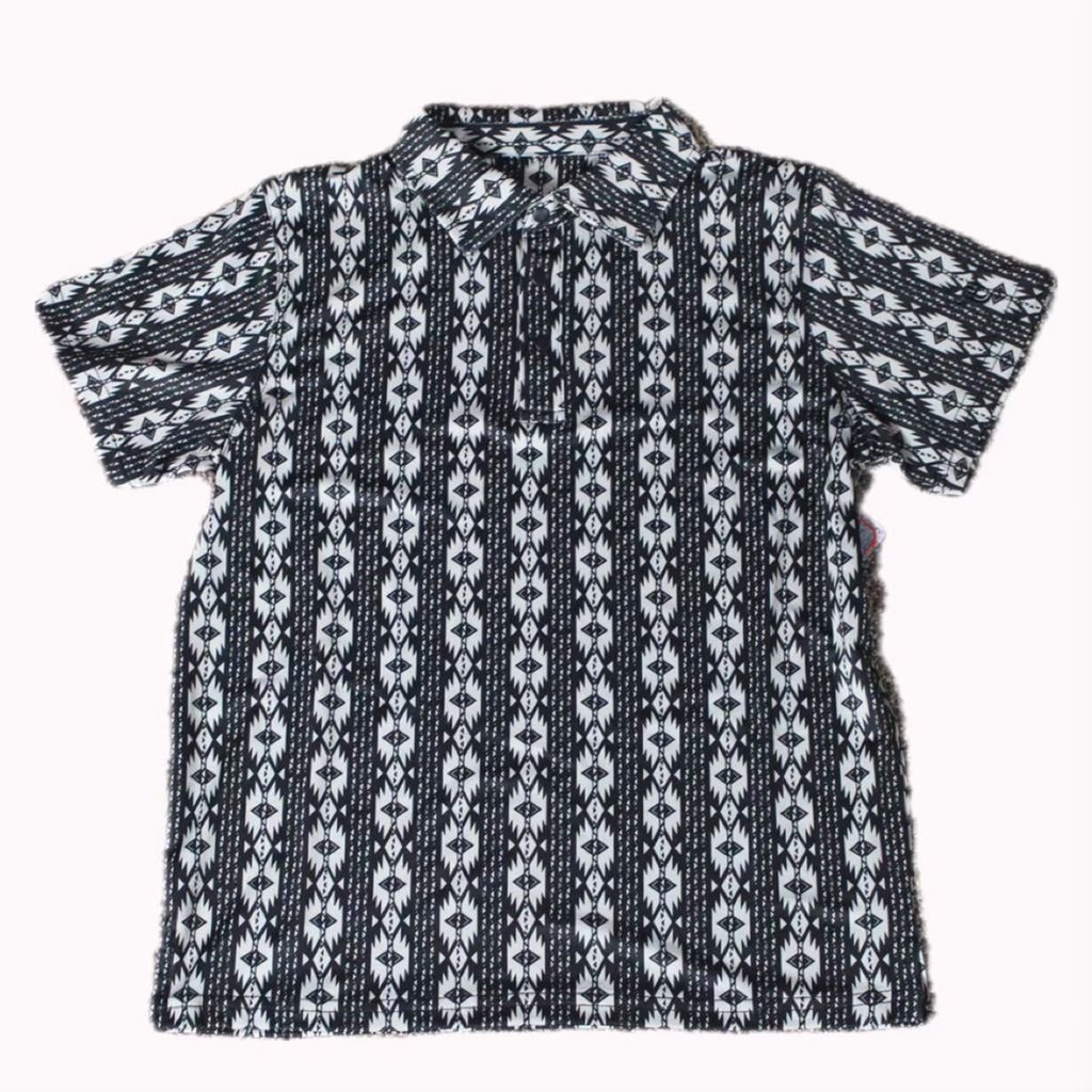 Flat lay of black polo shirt with white vertical Aztec designs. 