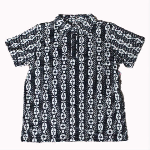 Flat lay of black polo shirt with white vertical Aztec designs. 