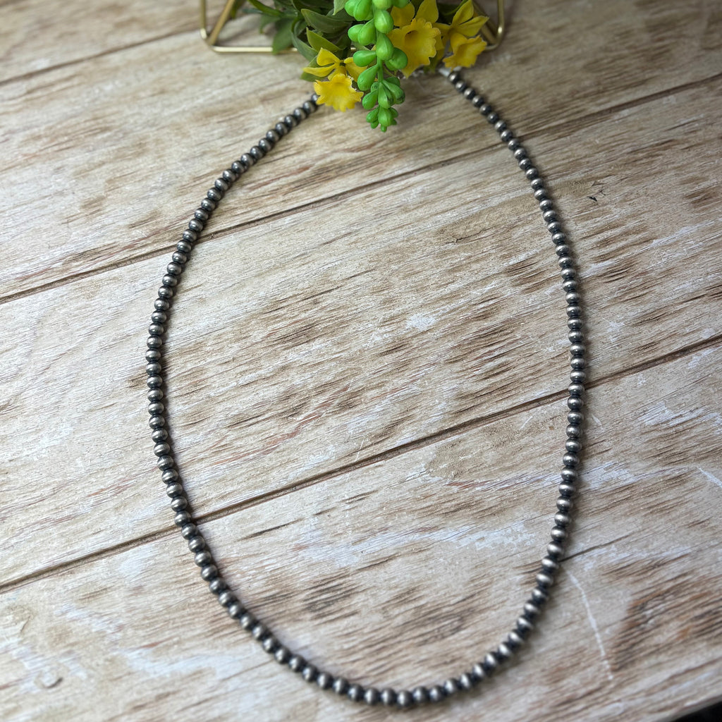 Flat lay of string of Navajo pearls. The necklace is 24 inches long ad the beads are 6mm.