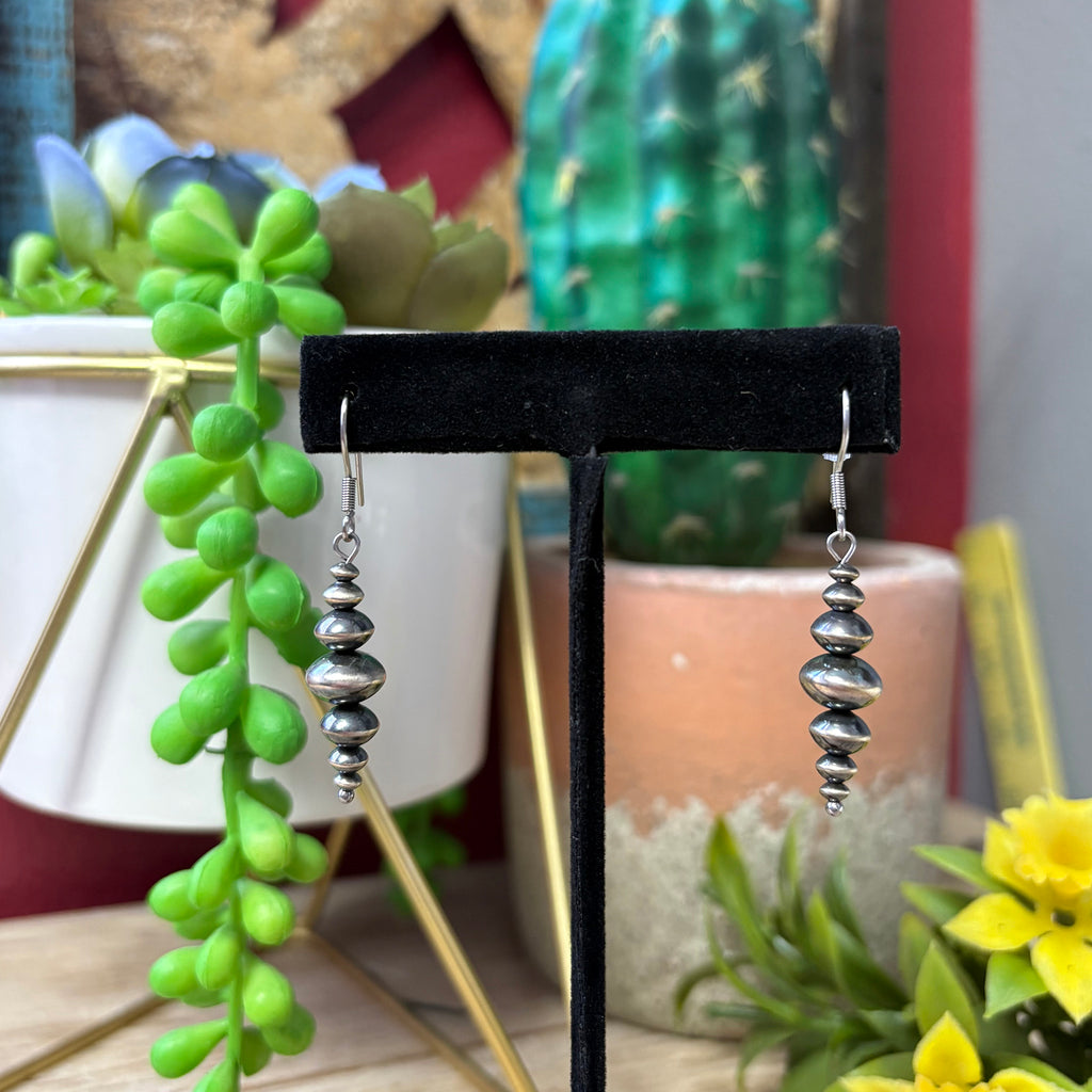 Navajo style pearl earrings that are graduated with the biggest pearl in the middle and smaller ones on the top and bottom. Pearls are also disc shaped. 
