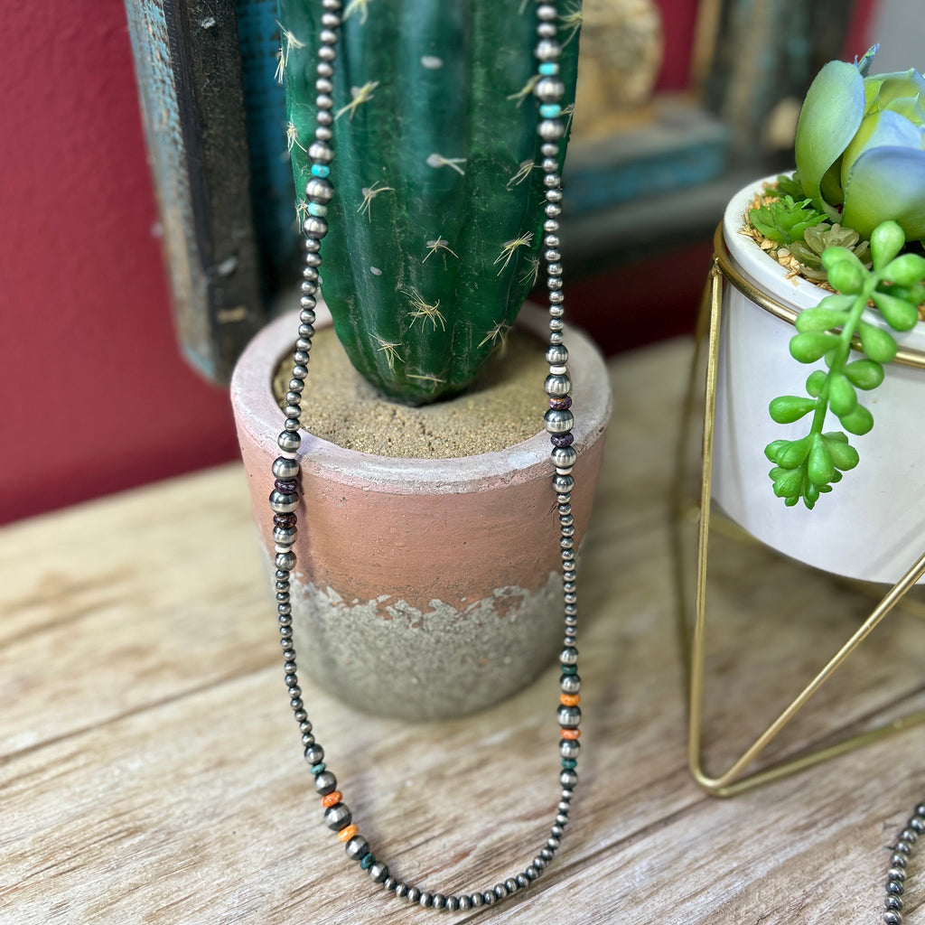 24" graduated Navajo pearl necklace that has green, blue, purple, and orange stones mixed in.