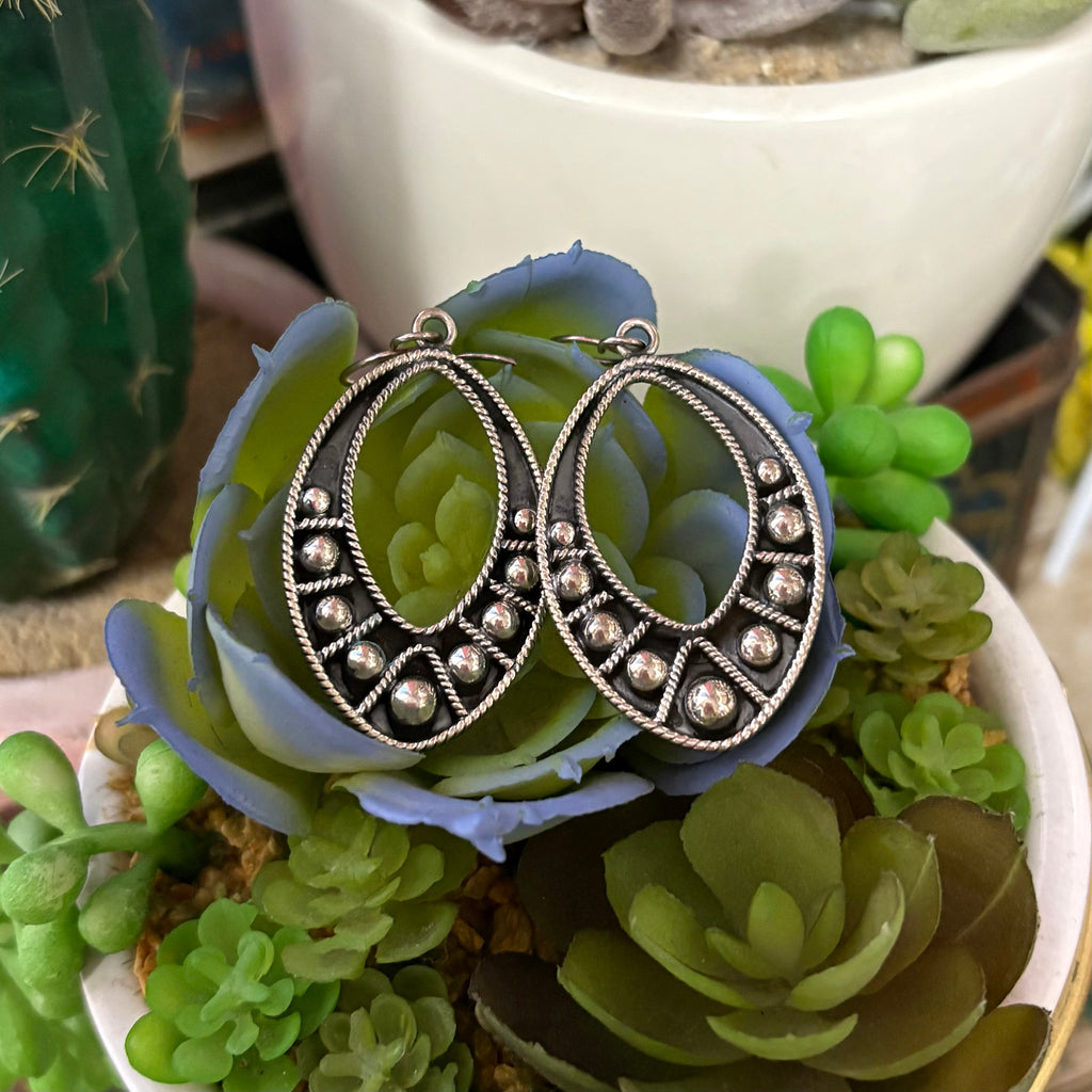 "Beverly" earrings sitting next to each other on a plant