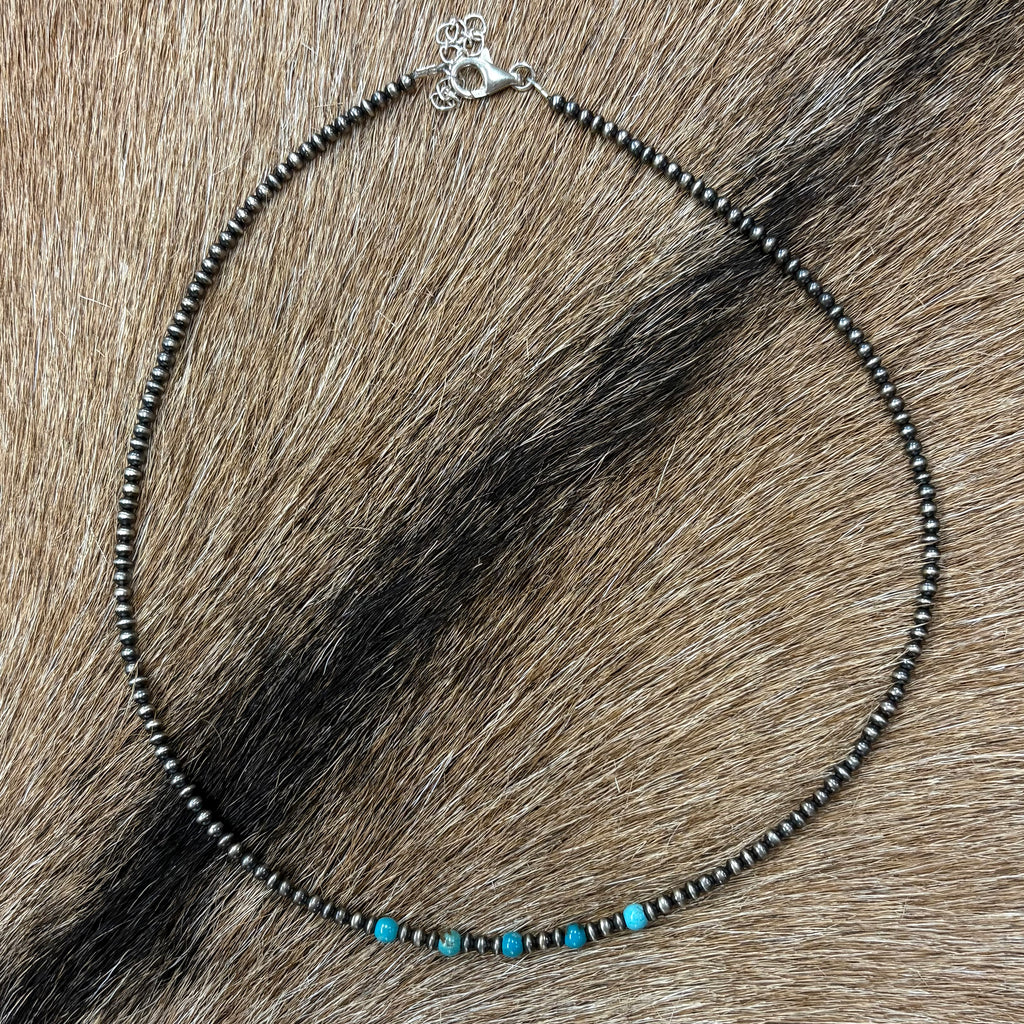 Full view of "Tamara" necklace laying on cowhide 