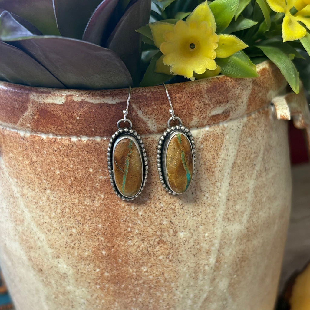 "Otto" Boulder Turquoise Long Oval Earrings hanging on vase. 