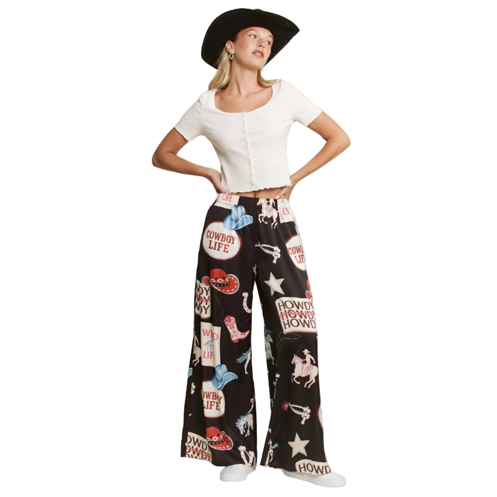 Woman wearing a white top and black patterned pants with cowboy-themed graphics