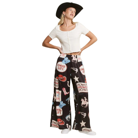 Woman wearing a white top and black patterned pants with cowboy-themed graphics