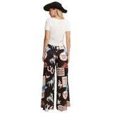 Baxk view of a woman wearing a white top and black patterned pants with cowboy-themed graphics