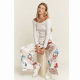 Woman wearing a white long-sleeve top and cream western graphic patterned pants