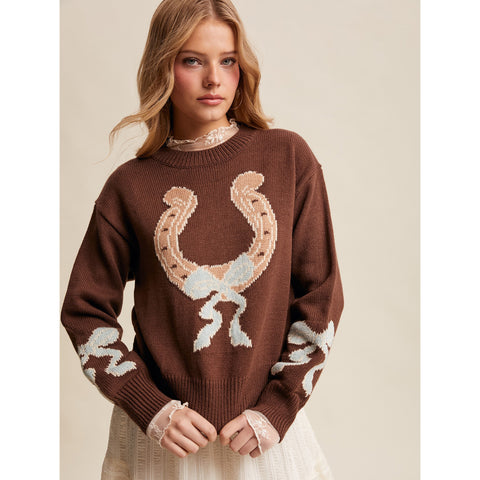woman wearing a brown sweater with a big horseshoe on the front with bow patterns on sleeves