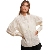 Womean wearing an off white lace blouse with ruffle front chest pockets