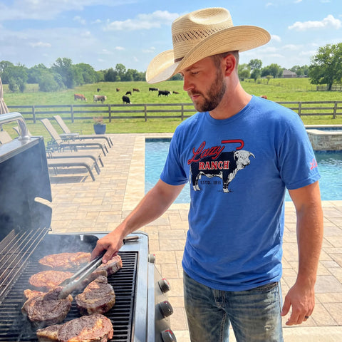 Model wearing the blue Lazy J Ranch Beefmaker T‑shirt in a casual outdoor setting, showing the soft fabric and easy Western everyday style.