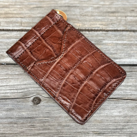 Brown leather cardholder with crocodile pattern on a wooden surface